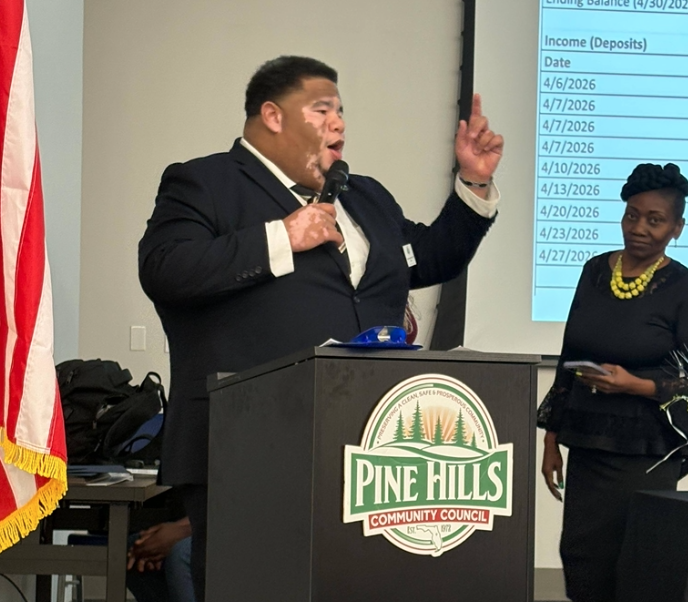 Julien speaking at a Pine Hills Community Council podium